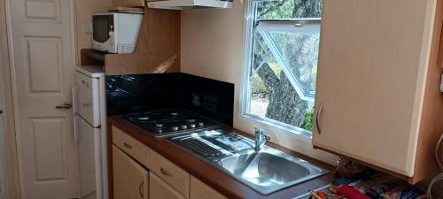 une cuisine avec un évier, une cuisinière et une fenêtre dans l'établissement Le Bungalow Bleu Domaine des Canebieres Golfe de St Tropez, au Muy