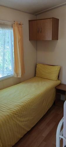 une chambre avec un lit jaune avec une fenêtre dans l'établissement Le Bungalow Bleu Domaine des Canebieres Golfe de St Tropez, au Muy