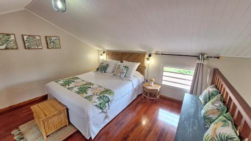 a bedroom with a large bed and a couch at Le Quéléa Une case créole de charme classée 4 étoiles Y être c'est y être bien in LʼEntre-Deux