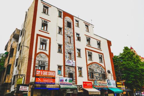 ein hohes weißes Gebäude mit Schildern davor in der Unterkunft Roomshala 155 Hotel JPC - Malviya Nagar in Neu-Delhi