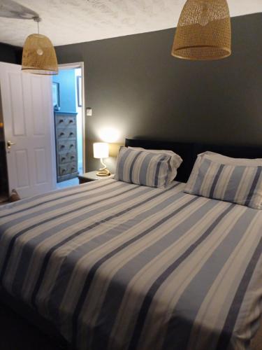 a bedroom with a bed with blue and white stripes at Black Pearl Apartment New Brighton in Wallasey