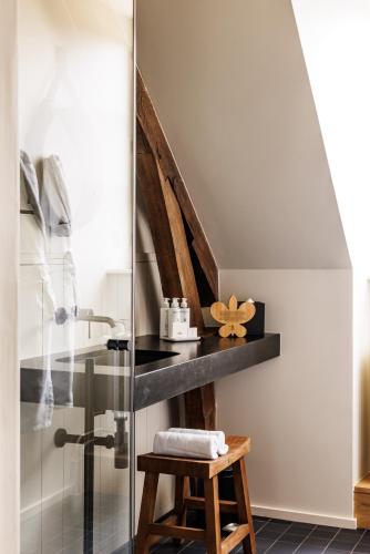 a bathroom with a glass shower and a stool at Domaine de Locguénolé & Spa - Relais & Chateaux in Kervignac