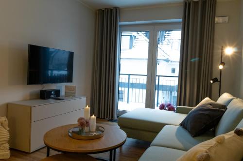 ein Wohnzimmer mit einem Sofa und einem TV in der Unterkunft Ferienwohnung Meerglück mit Balkon und Sauna - 300 m vom Strand entfernt in Kellenhusen