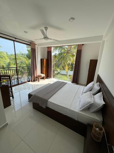 - une chambre avec un grand lit et une grande fenêtre dans l'établissement Shades Hotel & Villa, à Matara