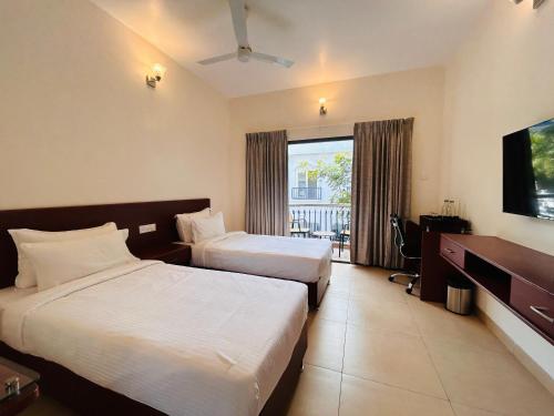 a hotel room with two beds and a television at Le MIAMI RESORT in Pondicherry