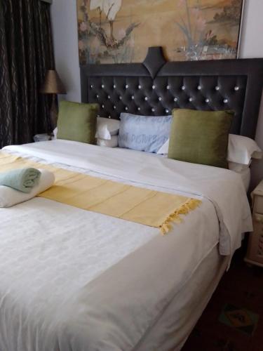 1 cama grande con sábanas blancas y almohadas verdes en norizana's apartment, en Westbrook
