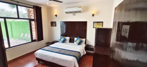 a bedroom with a bed and a large window at The Siyona Resort in Rāmnagar