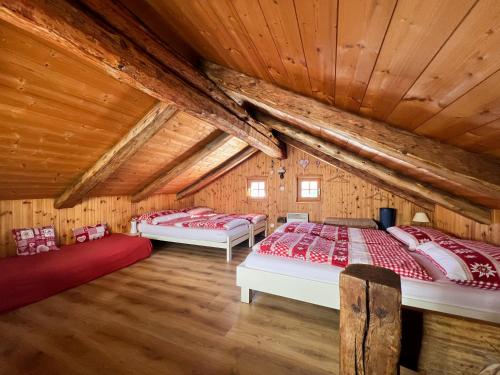 two beds in a room with wooden ceilings at Alphütte Bielerchäller in Fiesch