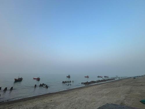 a group of boats in the water near a beach at Tapama Resort Bakkhali in Bakkhali