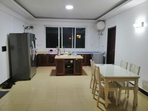 a kitchen with a table and a refrigerator and a table and chairs at Mariana Shared Home in Dar es Salaam