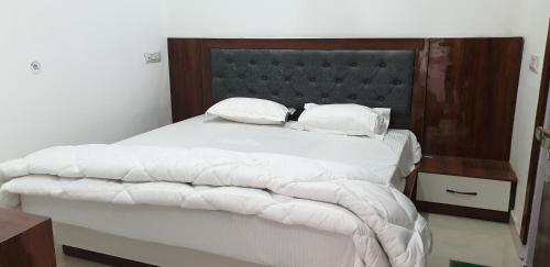 a bedroom with a large bed with white sheets and pillows at Modernio Guest House Noida Extension in Greater Noida
