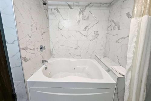 La salle de bains est pourvue d'une baignoire blanche et de murs en marbre. dans l'établissement Days Inn by Wyndham Berlin Meriden, à Berlin