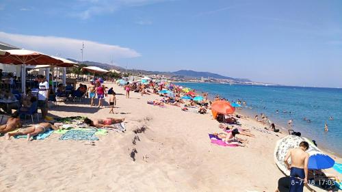 una folla di persone su una spiaggia con l'oceano di Hostal Estudios a Badalona
