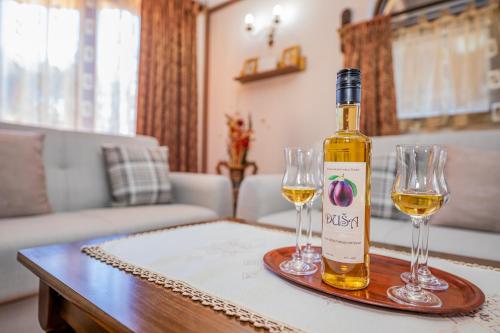 Vikendica Životić في زلاتيبور: زجاجة من النبيذ وكأسين من النبيذ على الطاولة