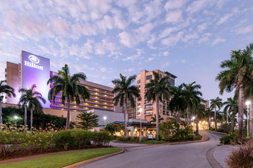 a building with palm trees in front of a road at Hilton Barbados Resort in Bridgetown