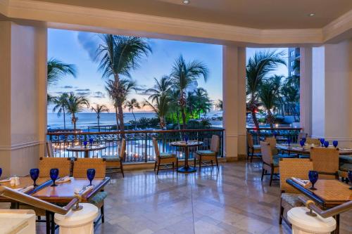 een restaurant met tafels en stoelen en uitzicht op de oceaan bij Hilton Barbados Resort in Bridgetown