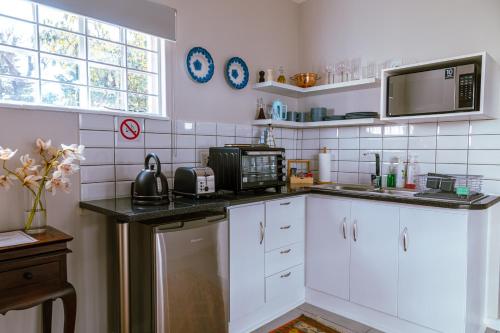 a kitchen with white cabinets and a black counter top at Fig Tree in Pretoria