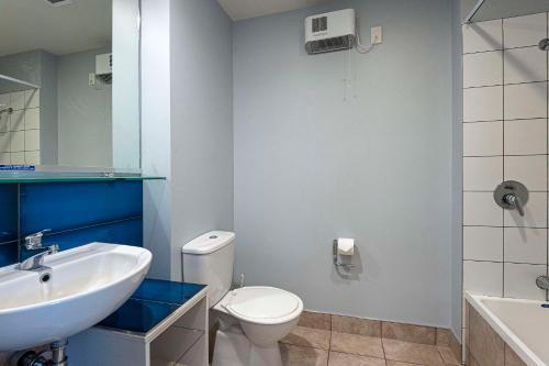 a bathroom with a white toilet and a sink at Quality Hotel Oceans Tutukaka in Tutukaka