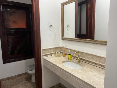 a bathroom with a sink and a mirror and a toilet at Casa na Praia Riviera de São Lourenço 4 Suítes para até 12 pessoas 4min a pé da Praia e 11 min a pé do Shopping in Riviera de São Lourenço