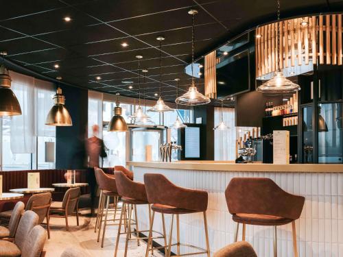 un restaurant avec des chaises et un bar avec des lumières dans l'établissement Novotel Angers Centre Gare, à Angers