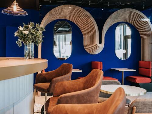 un restaurant avec des murs bleus, des chaises et des miroirs dans l'établissement Novotel Angers Centre Gare, à Angers