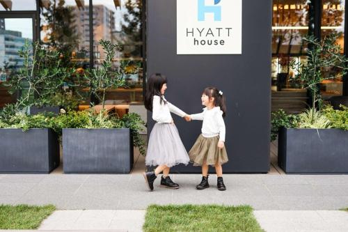 two little girls walking down a sidewalk holding hands at Hyatt House Kanazawa in Kanazawa