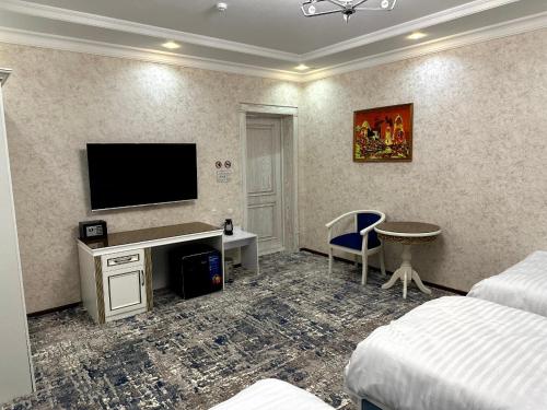 Una habitación de hotel con un escritorio y un televisor en la pared. en Gulnora HOTEL, en Uzbankinty