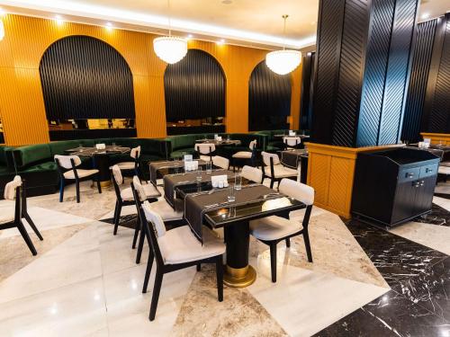 a restaurant with black tables and chairs and yellow walls at Mercure Baku City in Baku