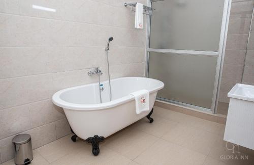 a white bath tub in a bathroom with a shower at Gloria Inn Hotel - Ndola in Ndola