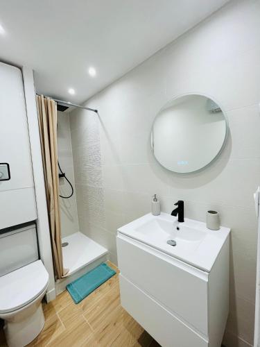 Baño blanco con lavabo y espejo en Appartement Cosy - Cap d'Agde proche plage et port - Parking en Cap d'Agde