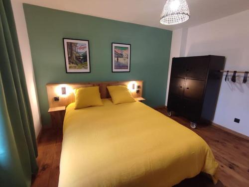ein Schlafzimmer mit einem gelben Bett mit zwei gelben Kissen in der Unterkunft Logement Spacieux in Fraize