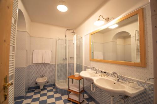 a bathroom with two sinks and a shower and a toilet at Hotel Vermoi in Laces
