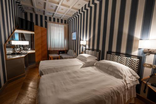 two beds in a hotel room with striped walls at Hotel S. Anna in Rome