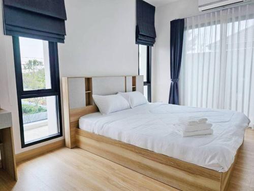 um quarto com uma cama com lençóis brancos e janelas em Kgrandville house-siri 