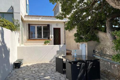 une table et des chaises devant une maison dans l'établissement Maison+terrasse au calme à 100m de l’eau, vue mer, à Marseille