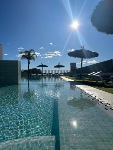 ein großer Pool mit Sonnenschirmen und der Sonne in der Unterkunft Turquesa del Mar - Max Beach Golf - Large Sunny Terrace Apartment in Playa Flamenca