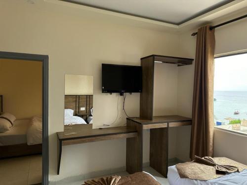 een kamer met een tv, een bed en een raam bij PALM BEACH HOTEL free ticket for pedal boat تذكرة مجانية للالعاب البحرية in Aqaba
