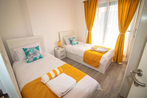 Imperial Resort, Eden في الغردقة: سريرين في غرفة صغيرة مع ستائر برتقالية