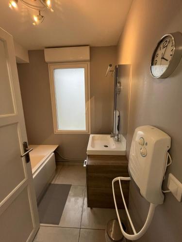 La salle de bains est pourvue de toilettes, d'un lavabo et d'une horloge. dans l'établissement La maison du bonheur 70 m², à Saint-Amand-les-Eaux