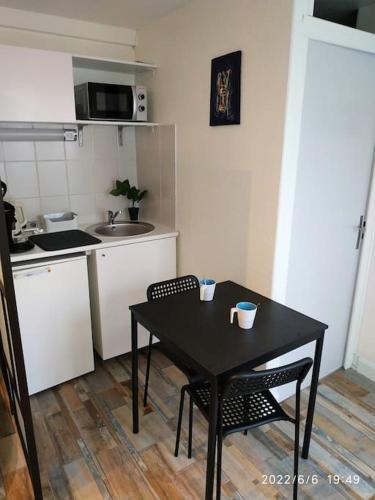 une cuisine avec une table et deux chaises et une cuisine avec un évier dans l'établissement Grand Studio avec jardin et entrée privative à noter réservations de 3 nuits minimum, à Clermont-Ferrand