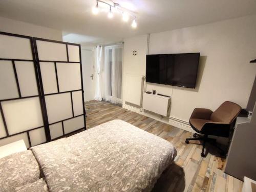 une chambre avec un lit, un bureau et une télévision dans l'établissement Grand Studio avec jardin et entrée privative à noter réservations de 3 nuits minimum, à Clermont-Ferrand