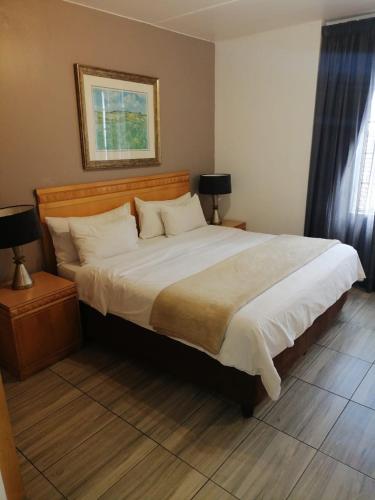 a bedroom with a large bed with two night stands and two lamps at Airport Inn and Suites in Johannesburg