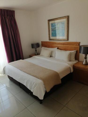 a bedroom with a large white bed with two lamps at Airport Inn and Suites in Johannesburg