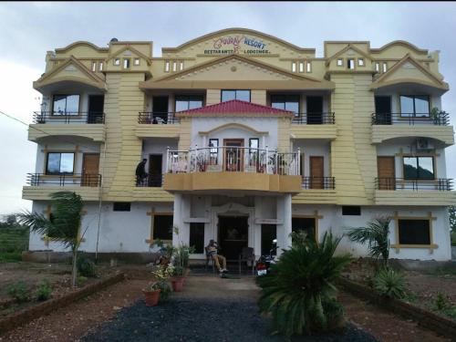 ein großes gelbes Gebäude mit einer Veranda und einem Balkon in der Unterkunft Gaurav Resort in Rāmtek