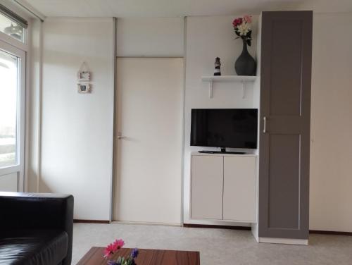 a living room with a television on a white wall at DUINZICHT 8 Bed by the Sea in Westkapelle