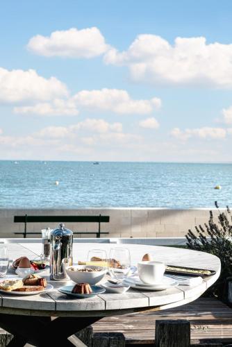 una mesa con comida y copas de vino en la playa en HR Hôtel-Restaurant & Spa Marin, en La Flotte