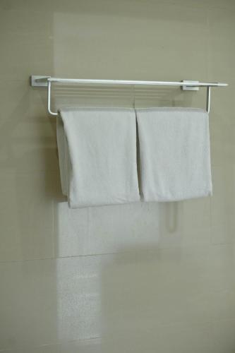 three towels are hanging on a towel rack in a bathroom at Noola Hotel Cilacap in Gumilir