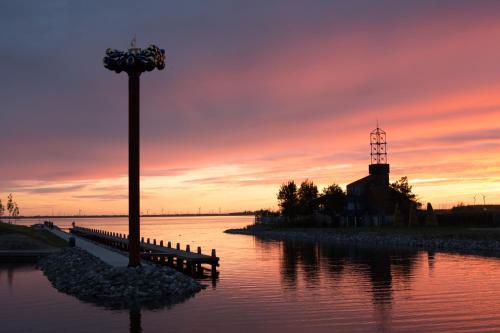 a sunset over a body of water with a light pole at Captains Boathouse in Harderwijk