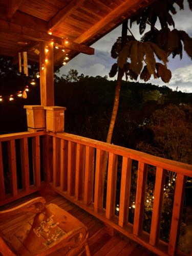 a wooden deck with a table and lights on it at Beehouse Arví Cabaña in Guarne