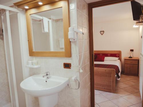 a bathroom with a sink and a mirror and a bed at La Majon de Fohten in Montjovet